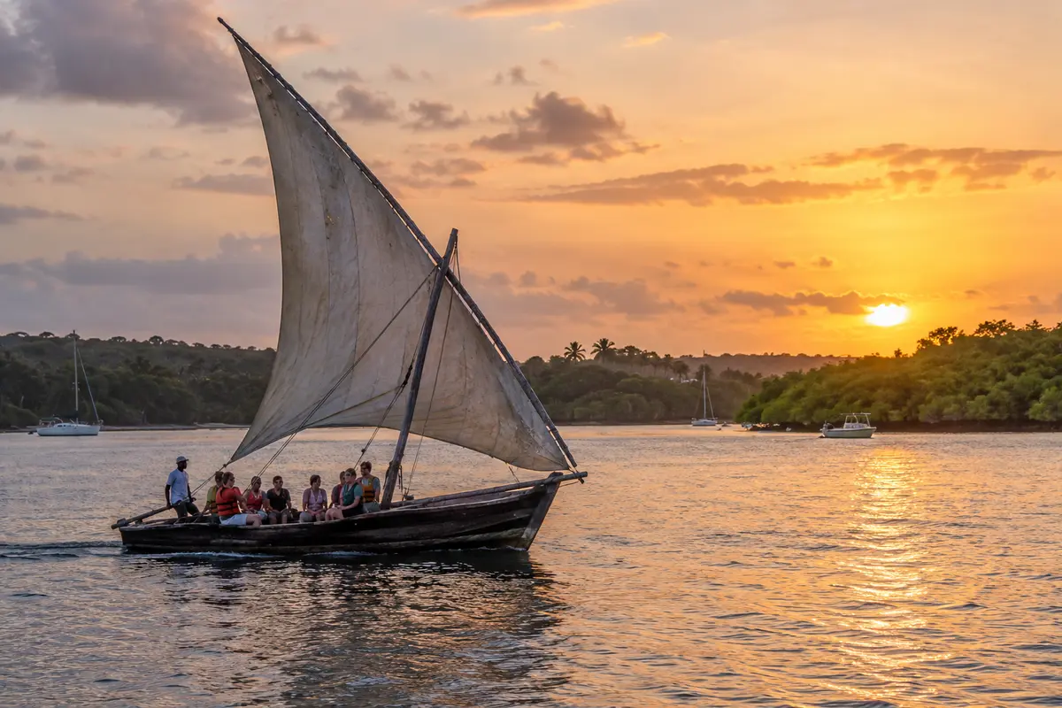 Traditional wooden dhow sailing across Kilifi Creek near sunset.