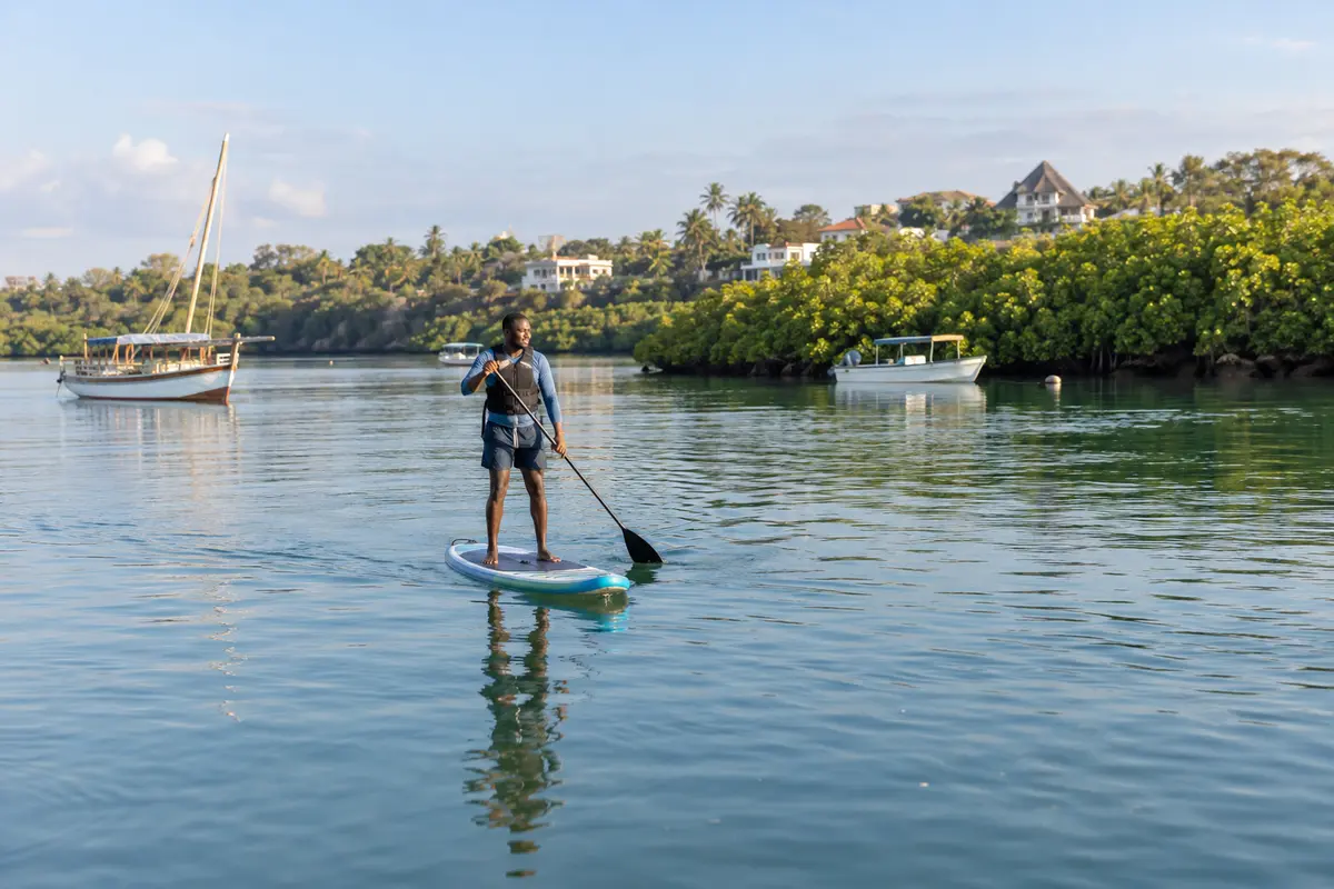 Stand-up paddleboarder crossing the sheltered water of Kilifi Creek.
