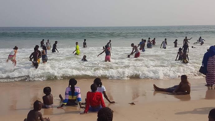 Visitors swimming and relaxing on a sandy beach beside the Atlantic Ocean in Lagos.