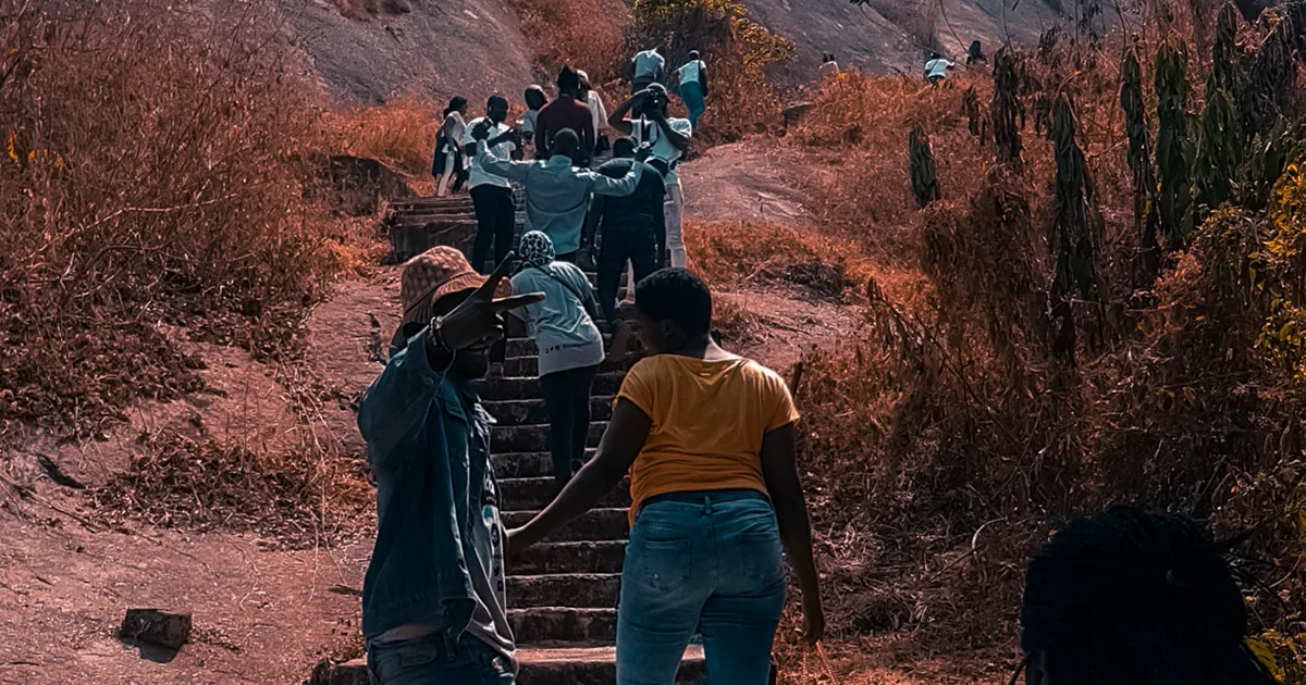Visitors climbing the steep stone steps between the reddish rock formations of Idanre Hills in Ondo State. Nigeria places