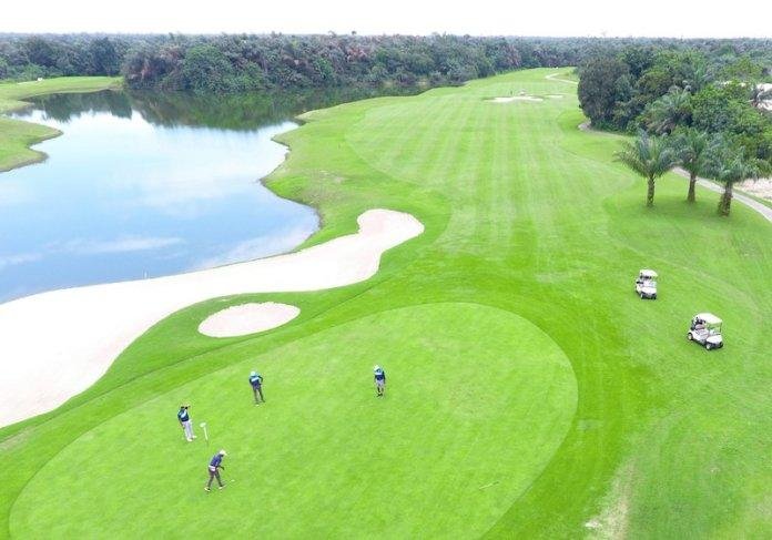 A golfer playing beside a lake on the green course at Lakowe Lakes in Lagos.